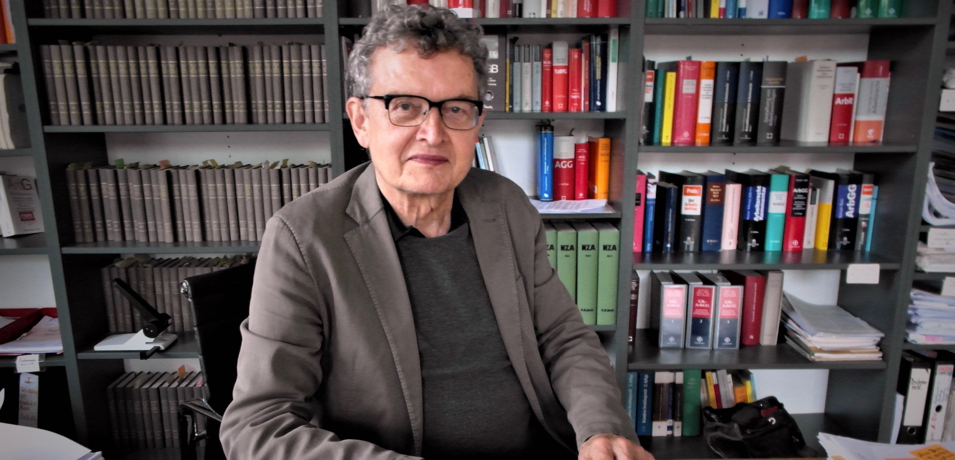 Henner Wolter in seinem Büro vor einem Regal voller Bücher